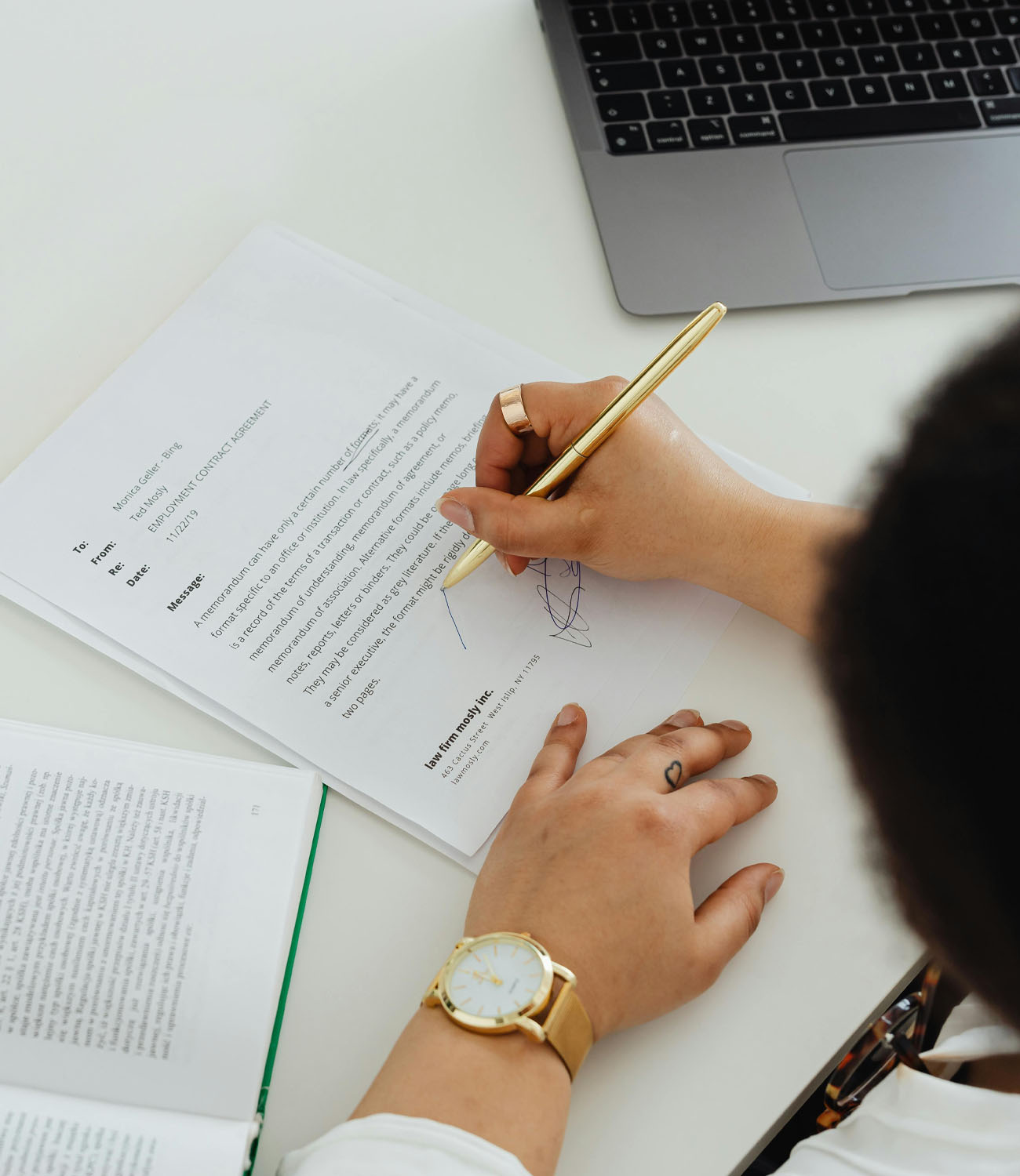 Persona firmando un documento con un bolígrafo dorado. Portada móvil.